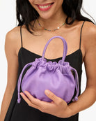 Person holding a purple drawstring bag against a white background