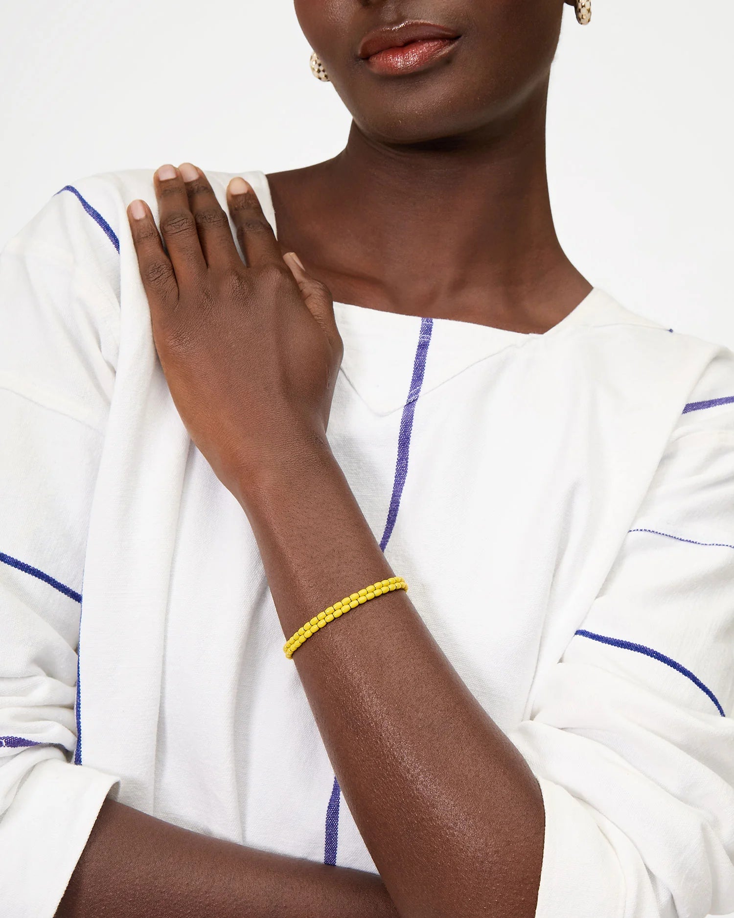 Person wearing a yellow bracelet on a white background