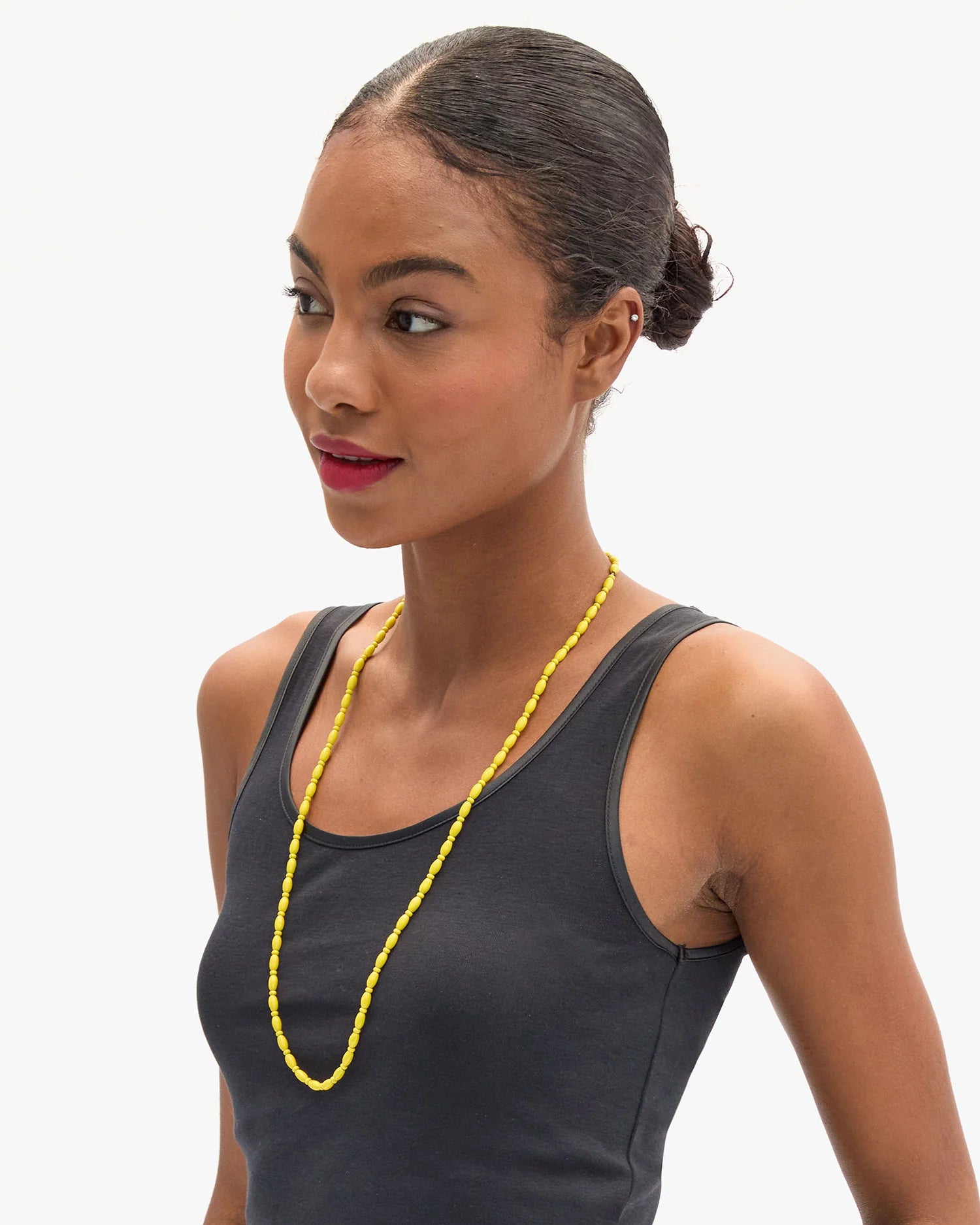 Woman wearing a yellow necklace against a white background