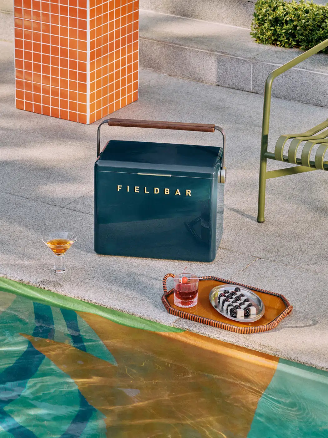 Blue cooler with 'FIELDBAR' branding by a poolside setting