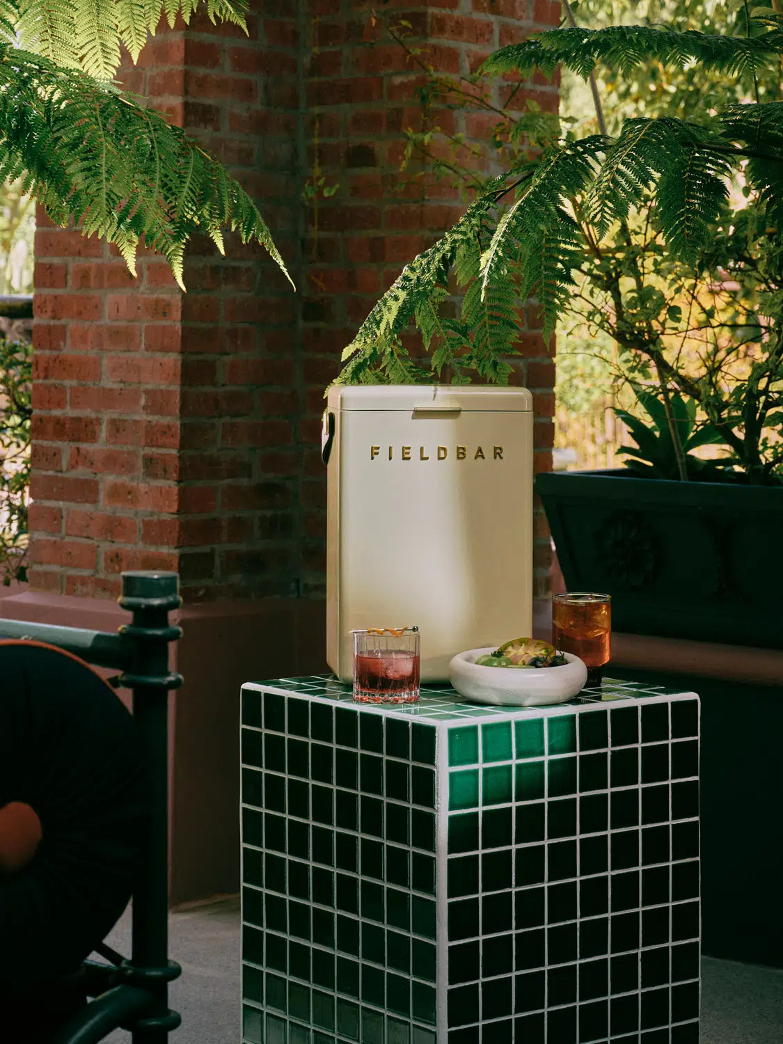 Outdoor setting with a 'Fieldbar' refrigerator, drinks, and snacks on a small table.