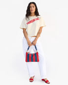 Woman holding a red and blue striped bag against a white background