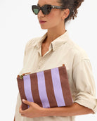 Woman holding a brown and purple striped clutch bag
