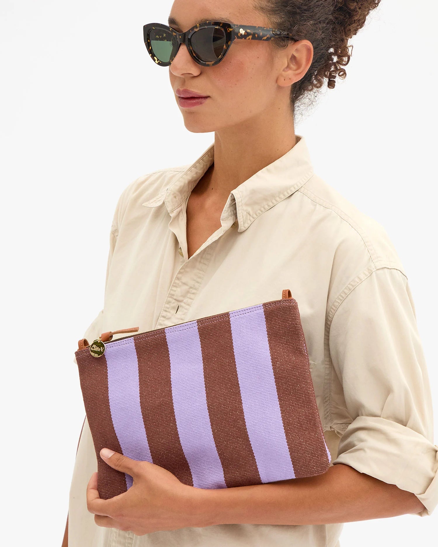Woman holding a brown and purple striped clutch bag