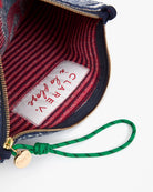 Close-up of a handbag with a visible brand label and green strap.