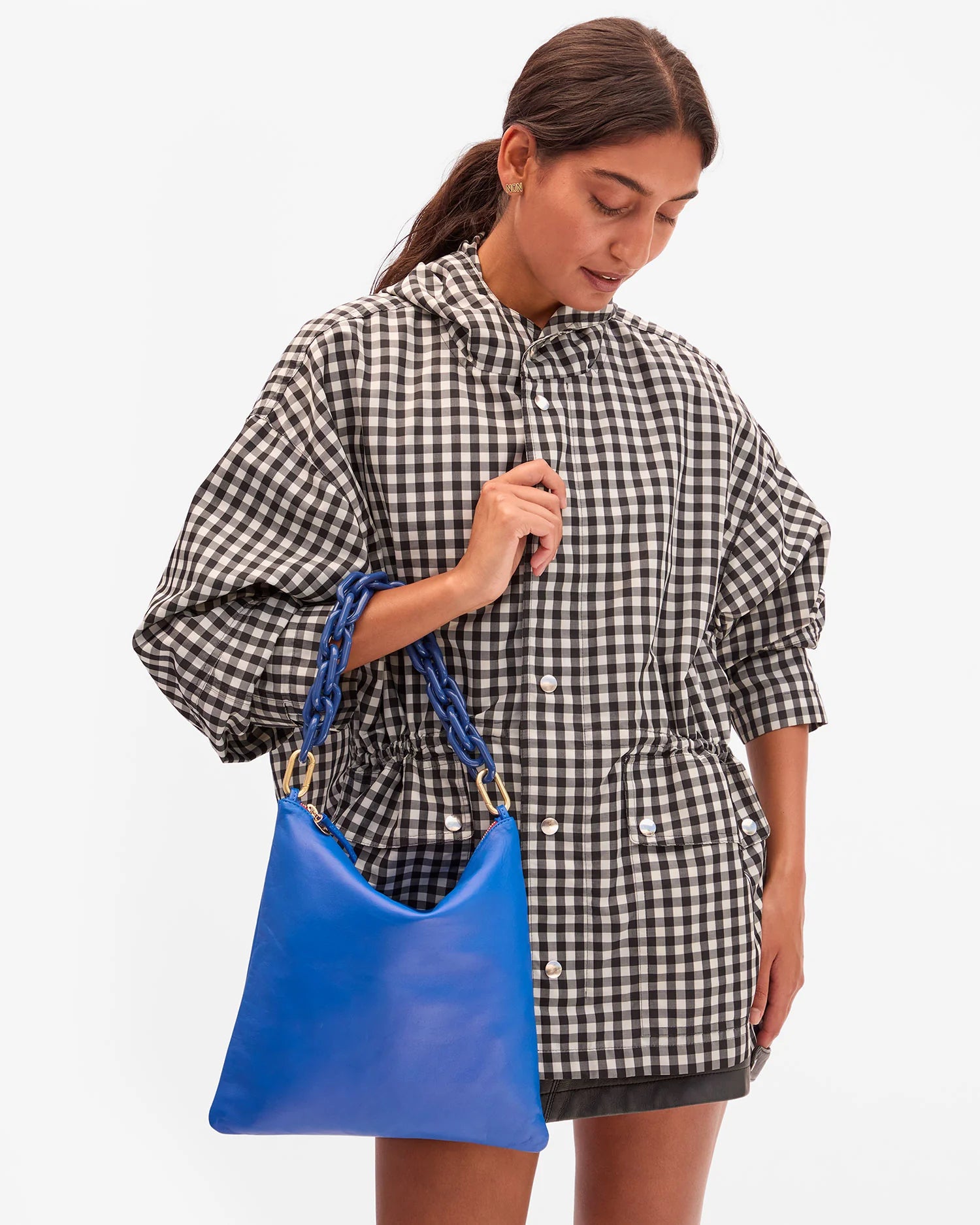 Woman holding a blue bag wearing a checkered raincoat on a white background