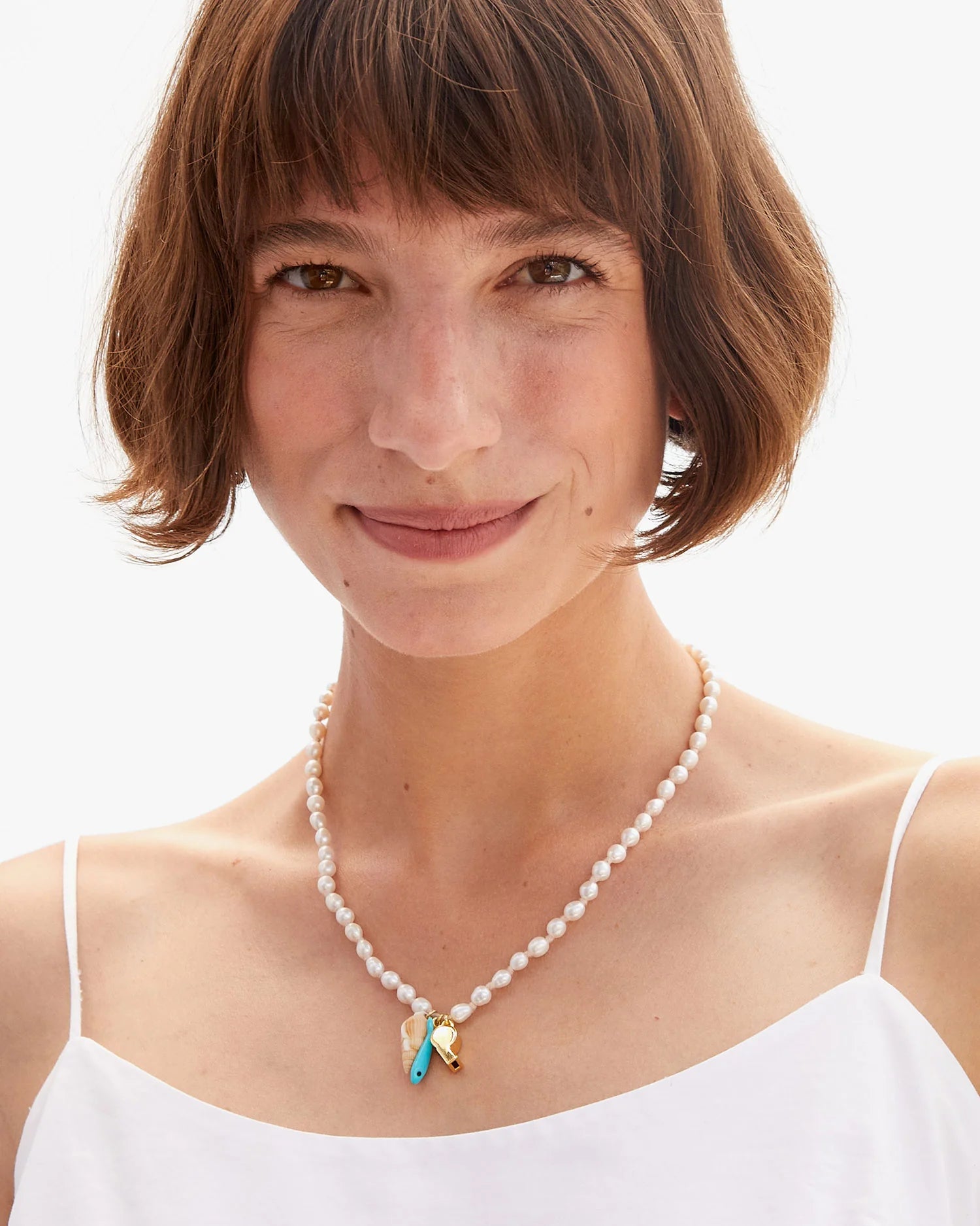 Woman wearing a pearl necklace with heart-shaped pendants on a white background