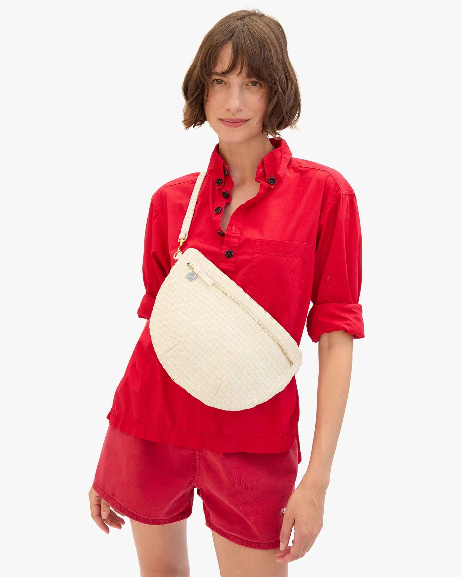 Woman wearing a red outfit with a white crossbody bag on a white background
