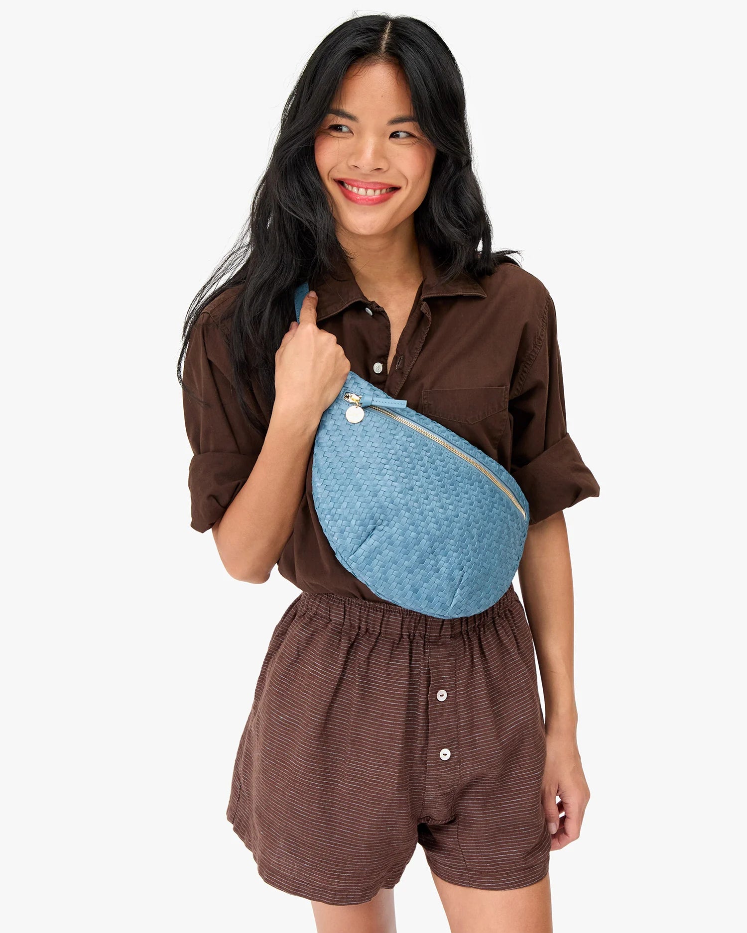 Woman wearing a brown outfit with a blue fanny pack on a white background