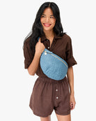 Woman wearing a brown outfit with a blue fanny pack on a white background