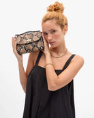 Woman holding a snakeskin pattern handbag against a white background
