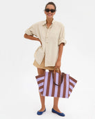 Woman holding a striped tote bag against a white background
