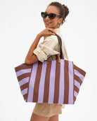 Woman holding a striped tote bag against a white background