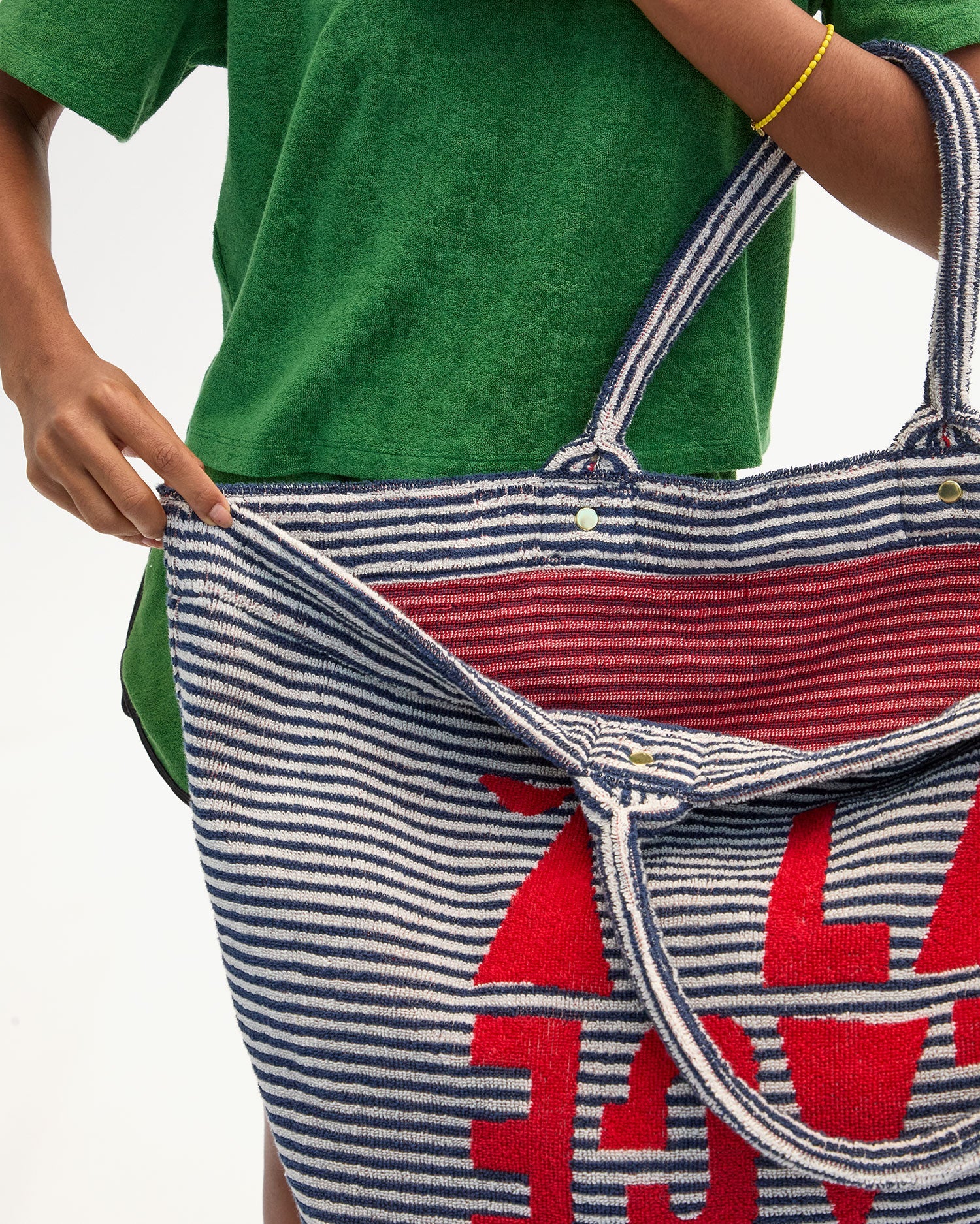 Person holding a striped tote bag with red text against a plain background