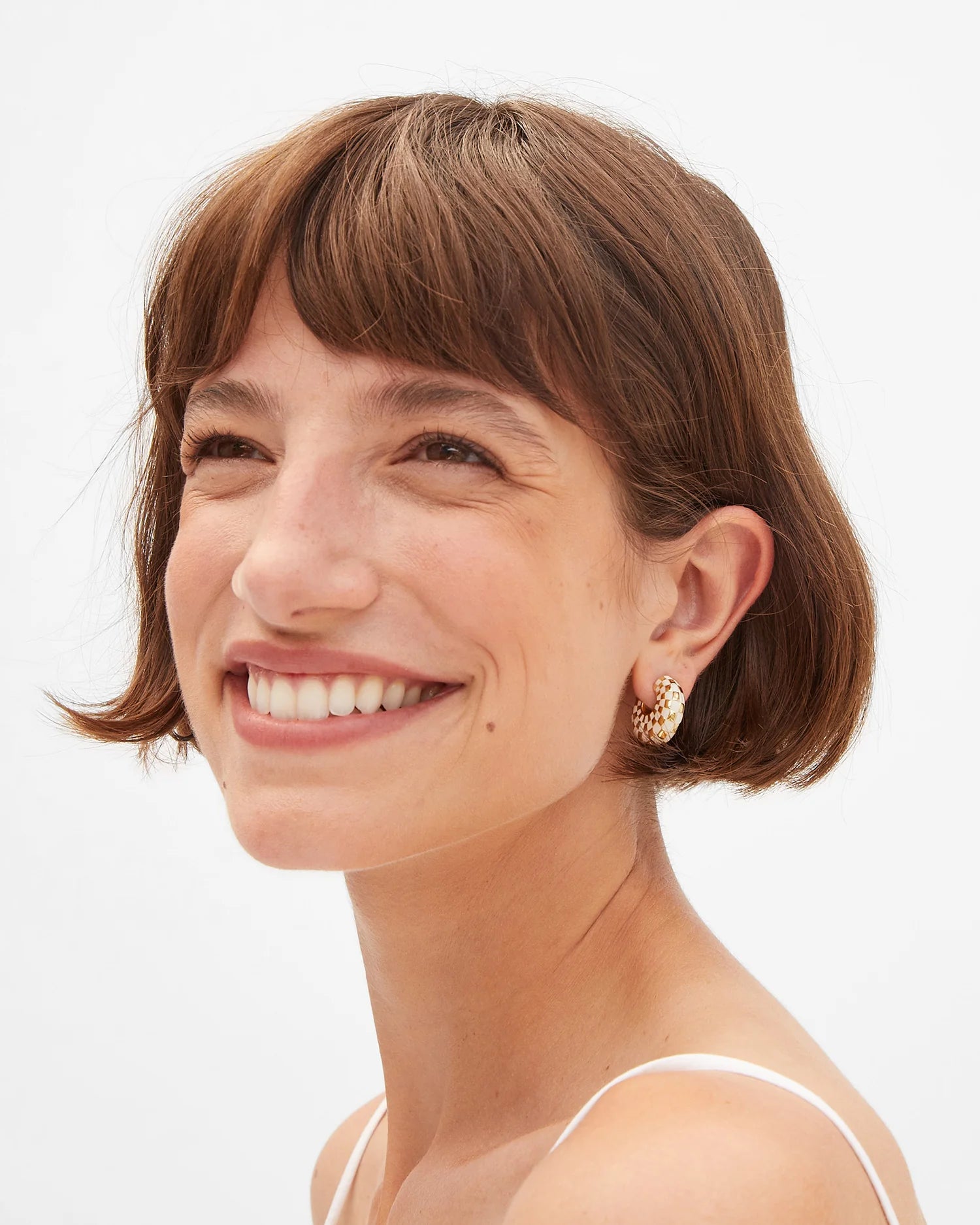 Woman with a short haircut and gold earrings on a white background