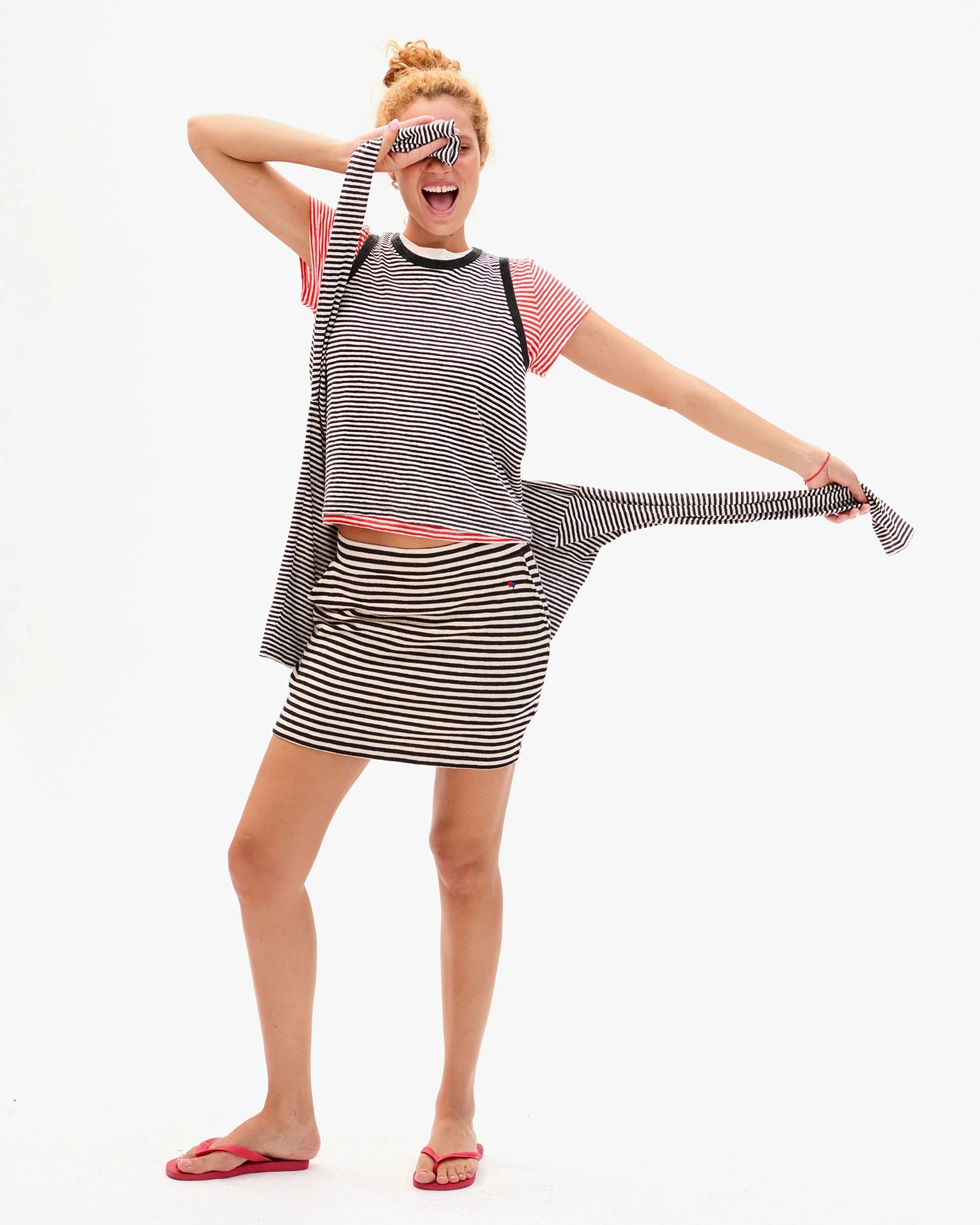 Woman stretching a long black and white striped dress against a white background