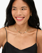 Woman wearing a colorful beaded necklace against a neutral background