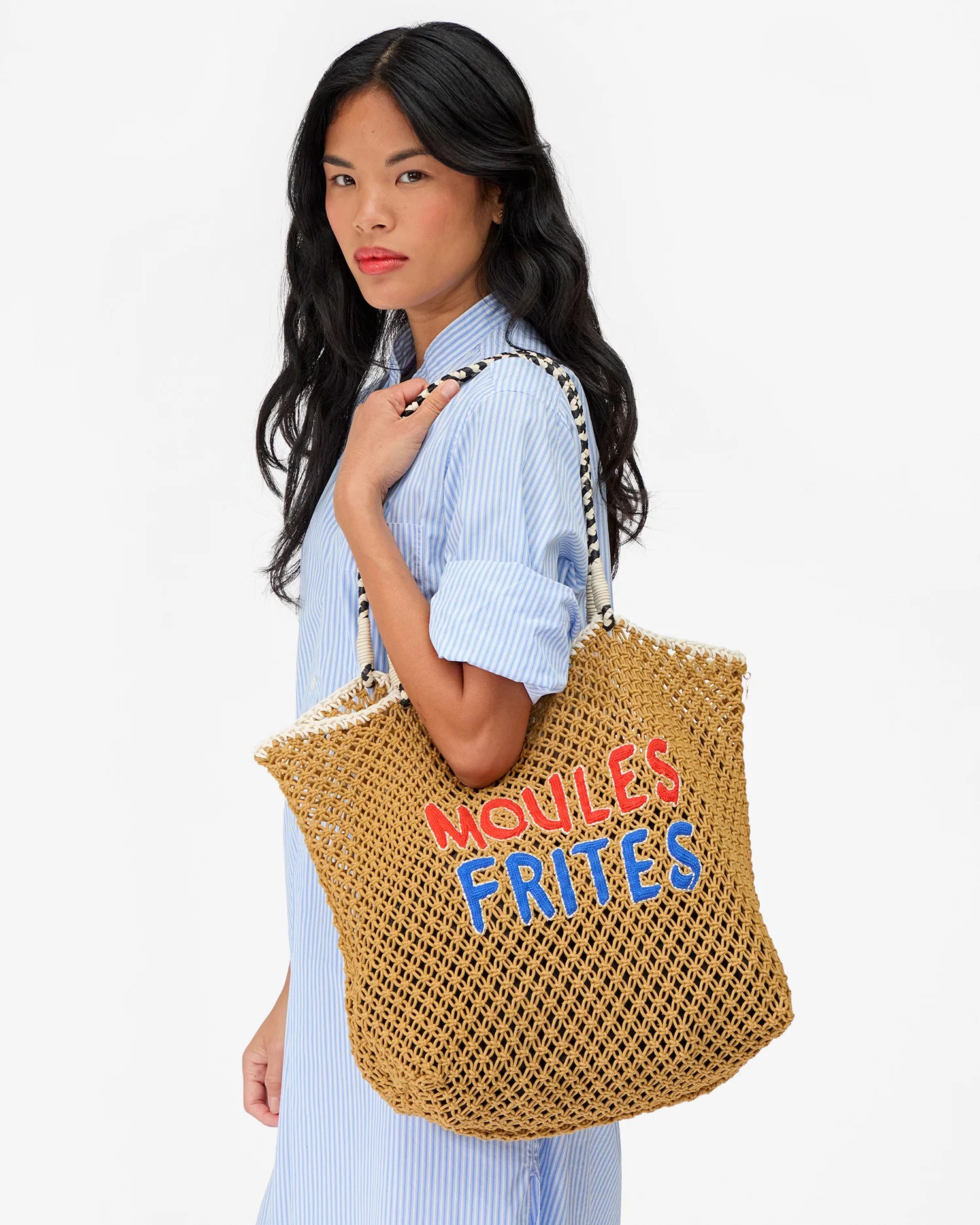 Woman holding a woven bag with colorful text against a white background