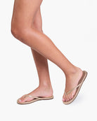 Person wearing beige flip-flops on a white background