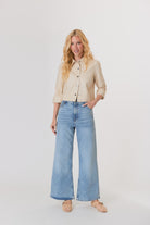 Woman wearing a beige jacket and light blue jeans on a white background