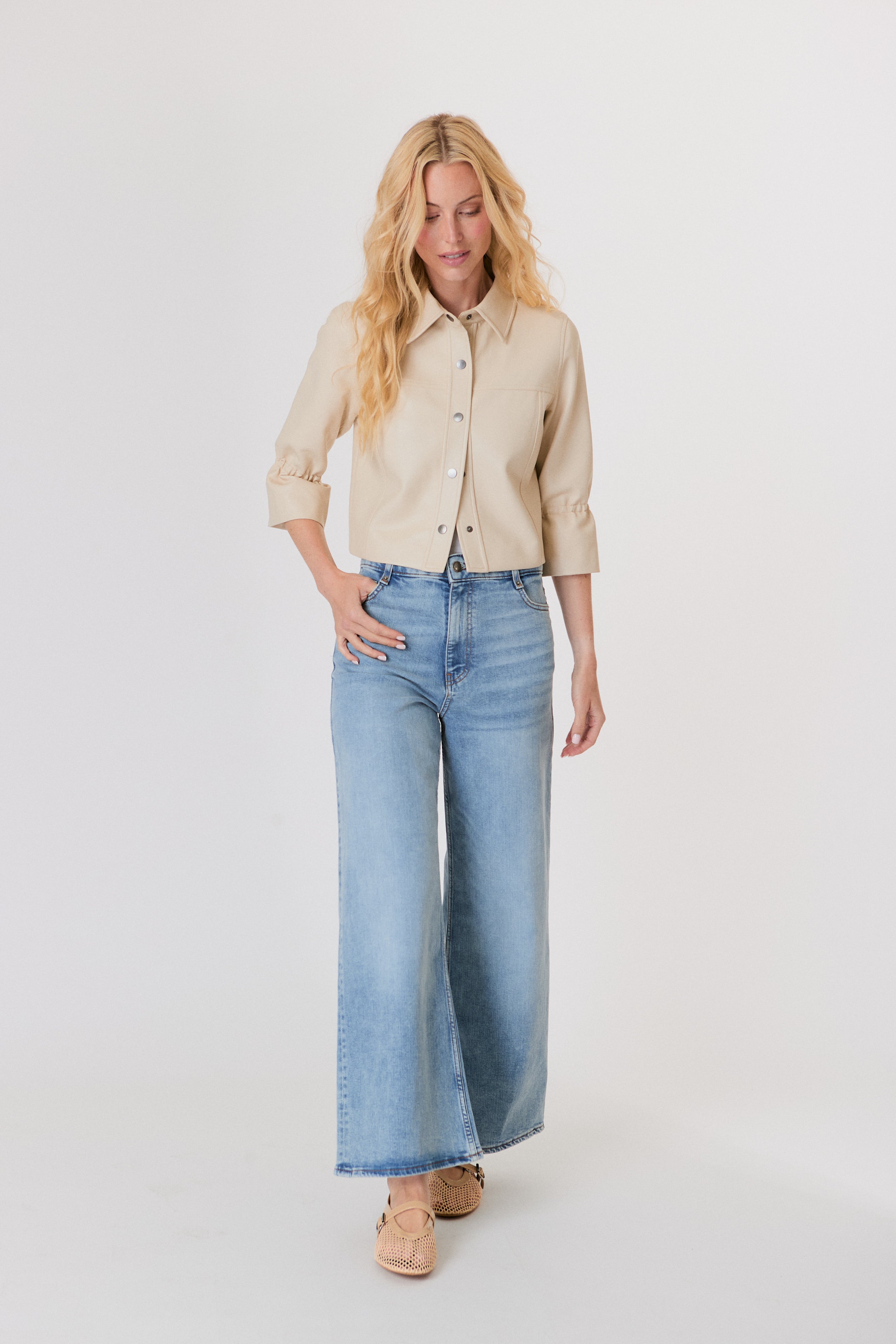 Woman wearing a beige shirt and blue jeans on a white background