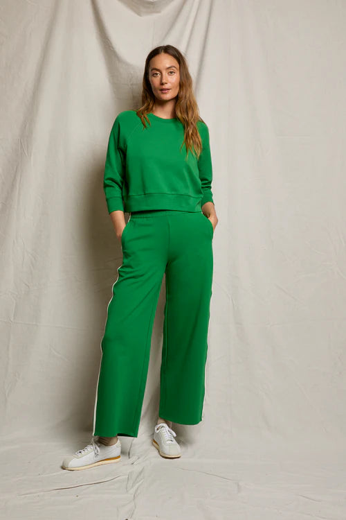 Woman wearing a green outfit standing against a plain background