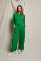 Woman wearing a green outfit standing against a plain background