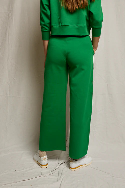 Person wearing a green outfit with wide-leg pants against a plain background