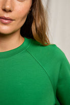 Person wearing a green sweater with a neutral background