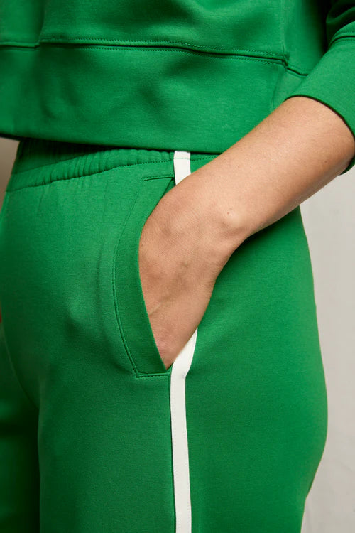 Green tracksuit with white stripe on a neutral background