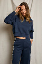 Woman wearing a navy blue tracksuit against a beige background