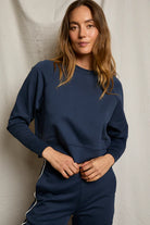 Woman wearing a navy blue outfit against a neutral background