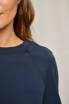 Navy blue long-sleeve top worn by a person against a neutral background