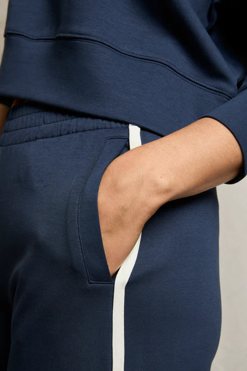 Navy tracksuit with white stripe on a neutral background