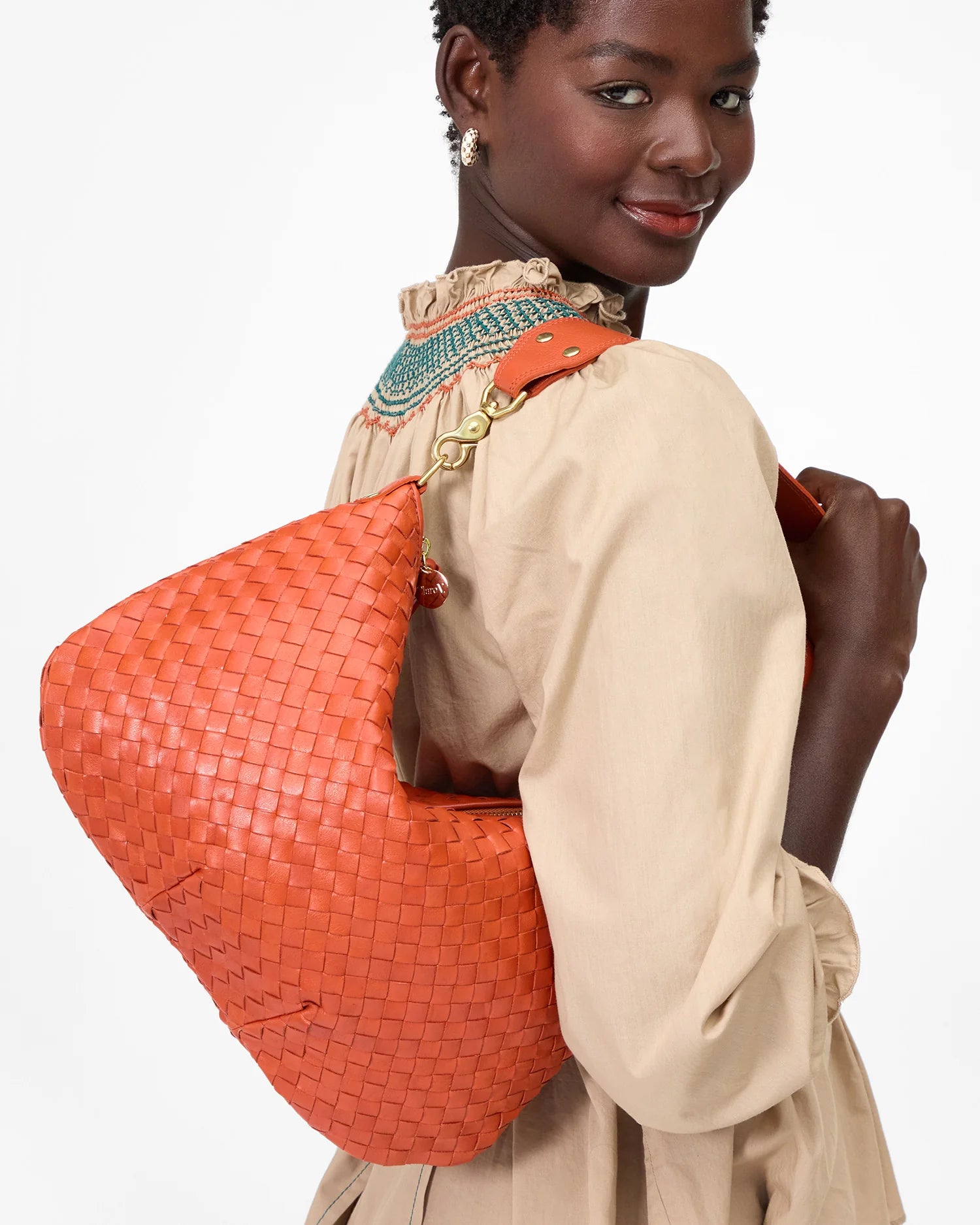Woman carrying an orange woven handbag on a white background