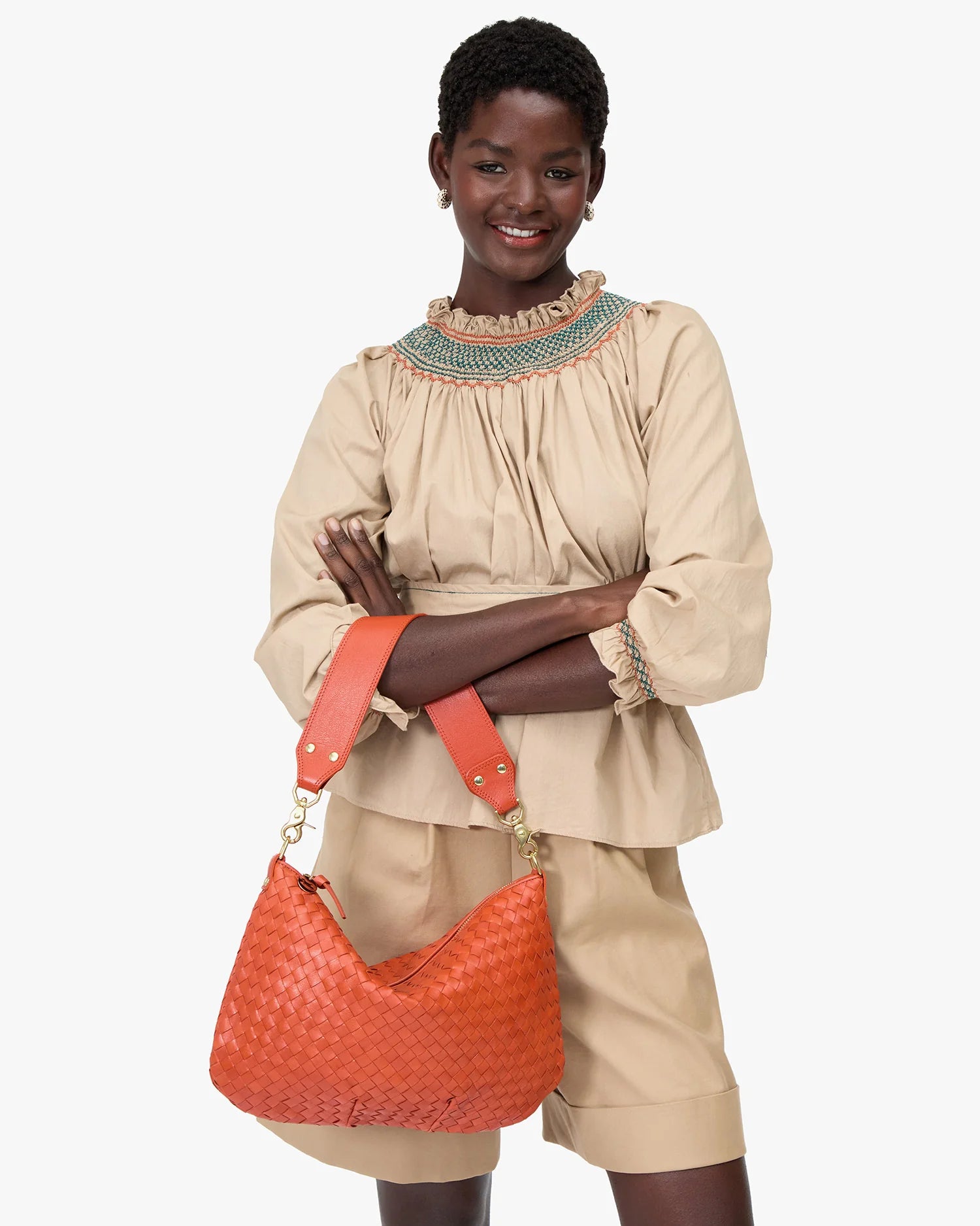 Woman holding an orange handbag against a white background