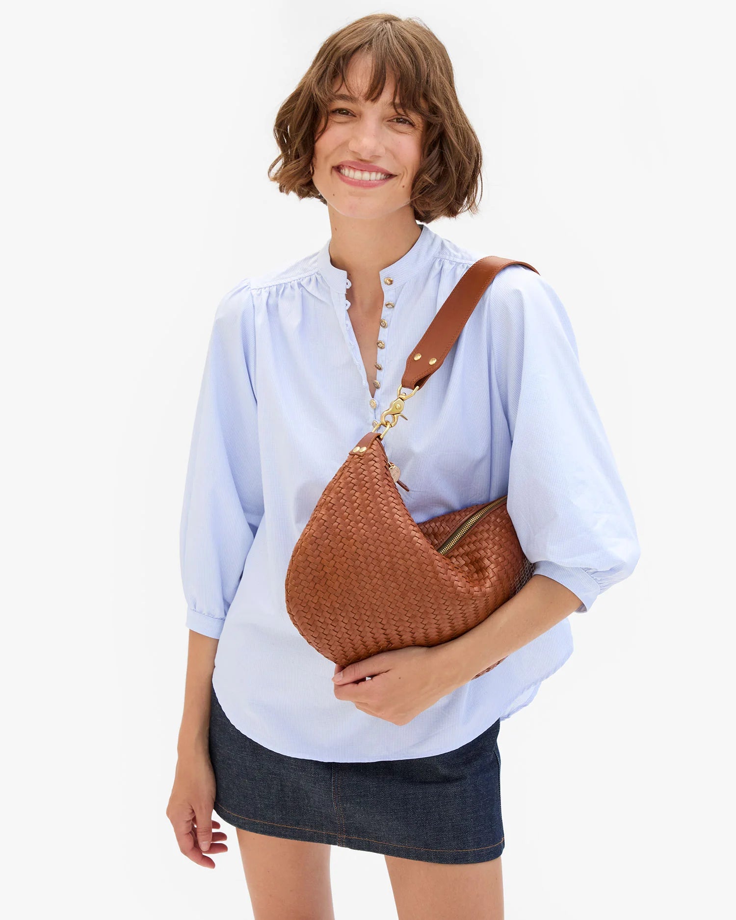 Woman holding a brown woven handbag against a white background