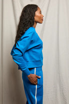Person wearing a blue tracksuit against a plain background
