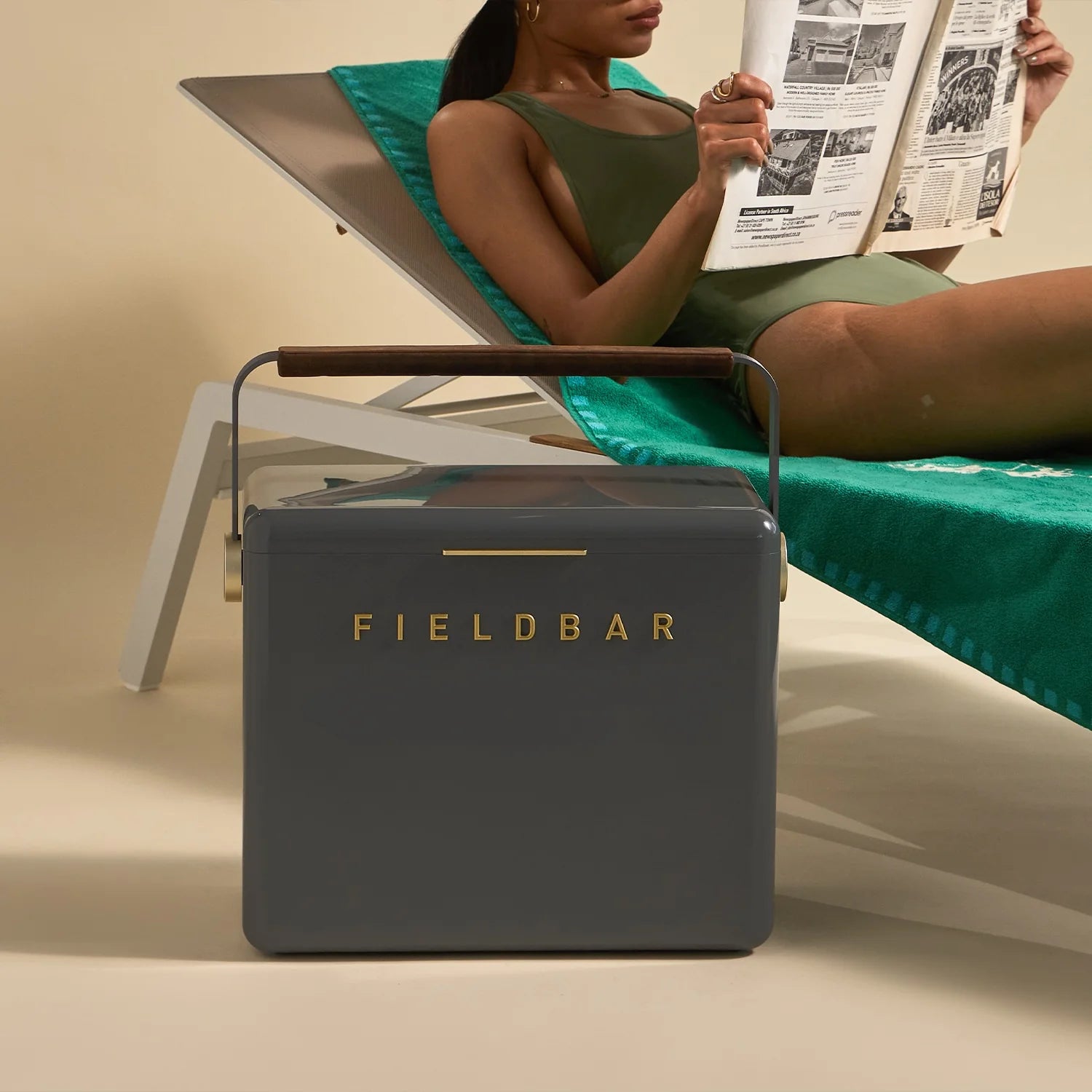 Woman reading a newspaper on a lounge chair with a Fieldbar product in the foreground.