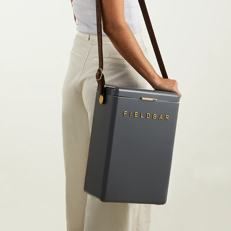 Person holding a gray cooler bag with 'FIELDBAR' branding on a light background