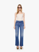Woman wearing blue jeans and a white top on a white background