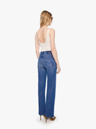 Woman wearing blue jeans and a white top on a white background