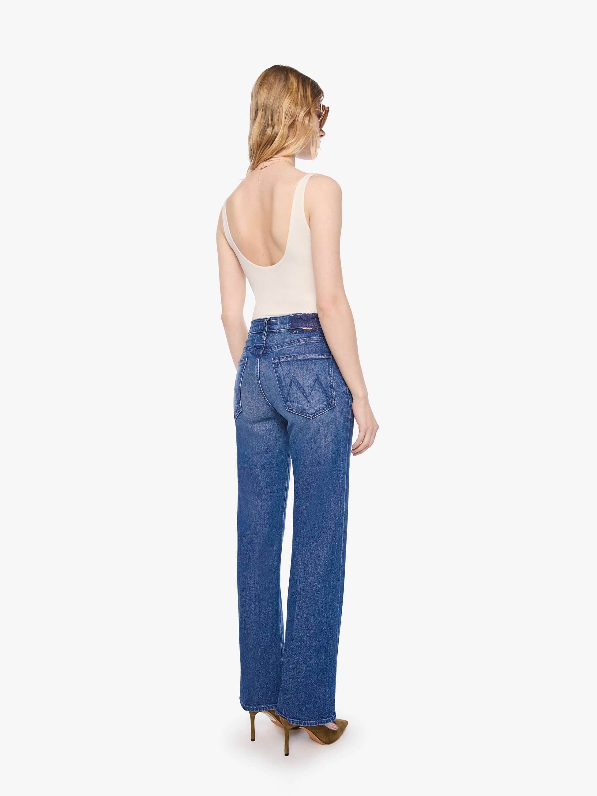 Woman wearing blue jeans and a white top on a white background