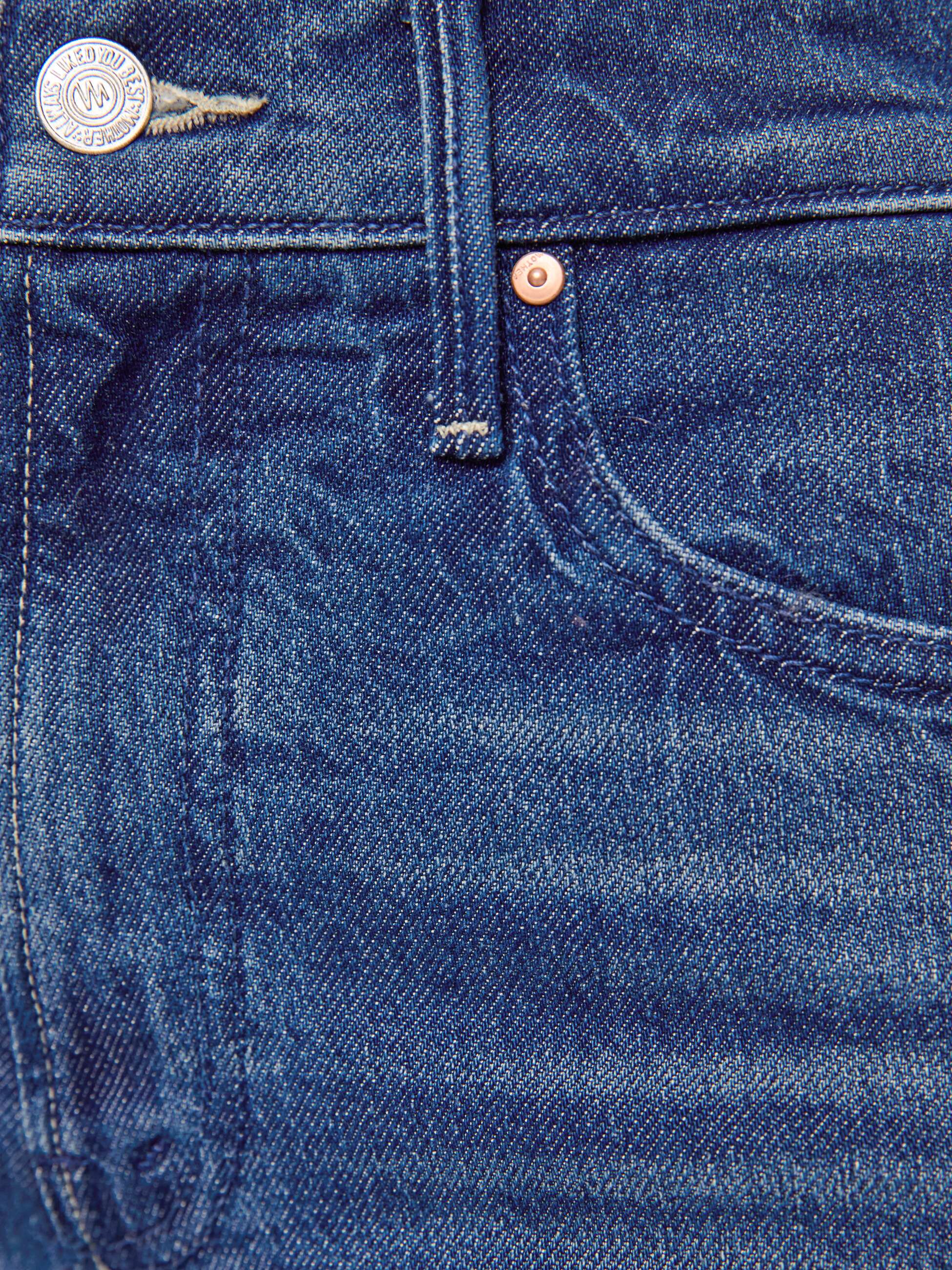 Close-up of blue denim fabric with button and stitching details
