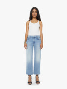 Woman wearing light blue jeans and a white top on a white background