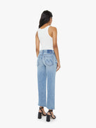 Woman wearing light blue jeans and a white top on a white background