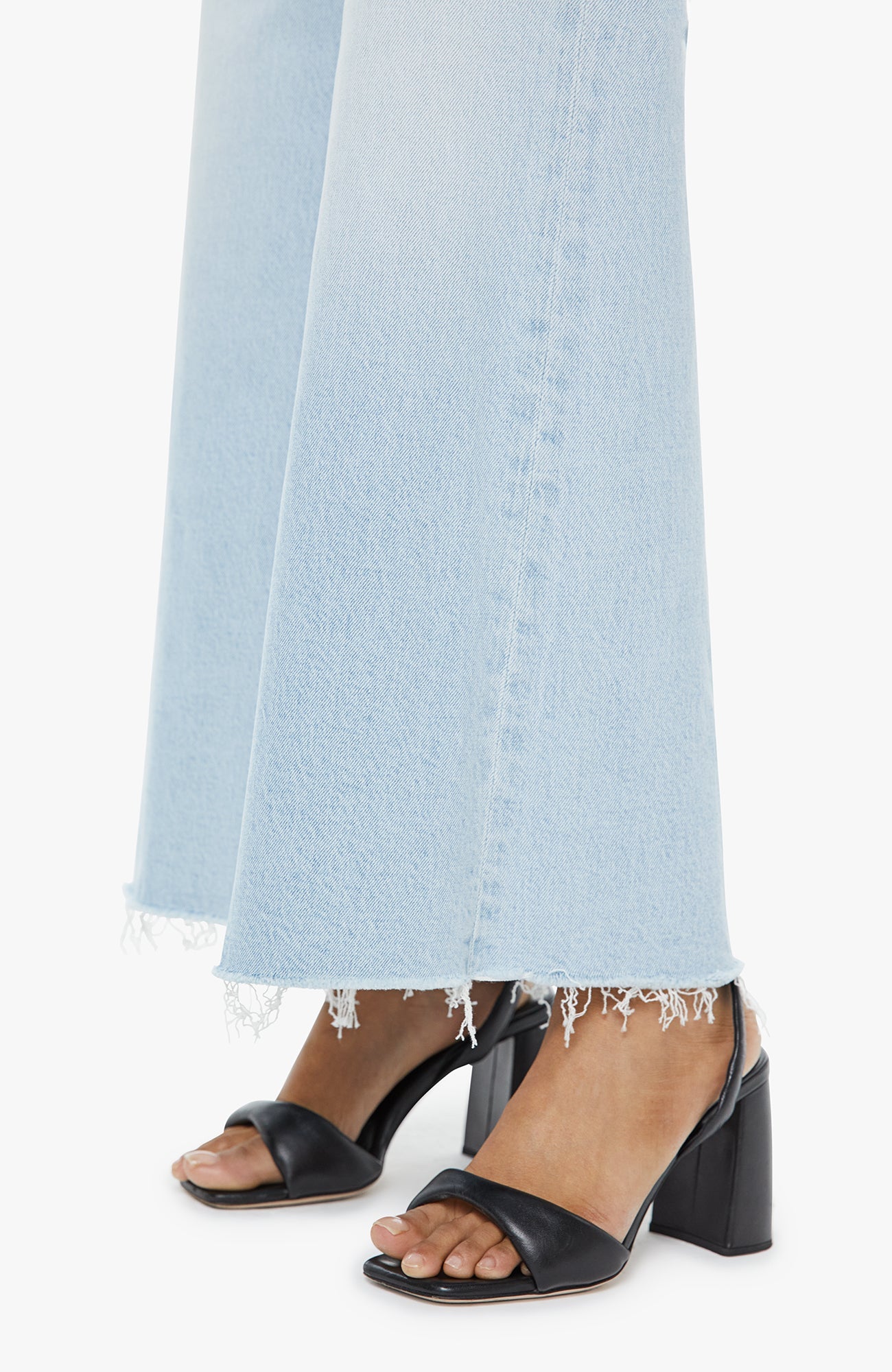 Black block-heel sandals worn with light blue jeans on a white background