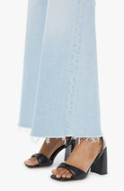 Black block-heel sandals worn with light blue jeans on a white background