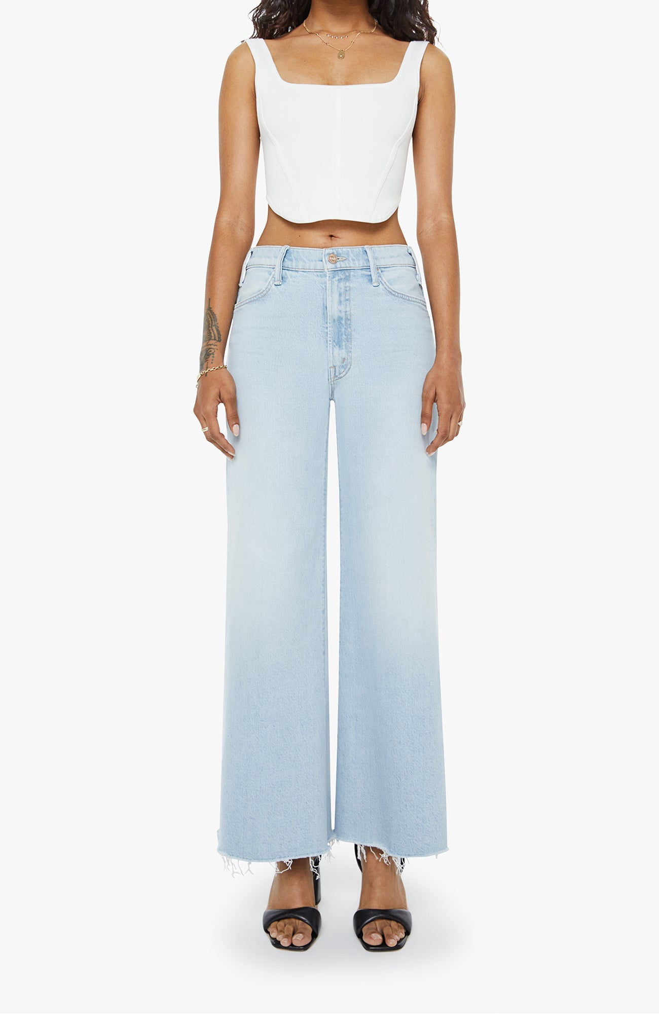 Person wearing a white crop top and light blue wide-leg jeans on a white background