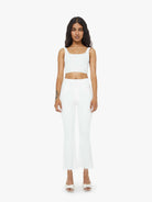 Woman wearing a white sleeveless top and long white pants on a white background